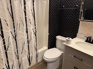 full bathroom featuring toilet, vanity, shower / bath combo, and hardwood / wood-style flooring