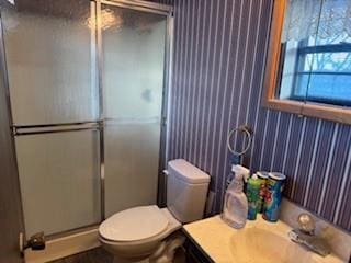 bathroom featuring toilet, a shower with door, and vanity