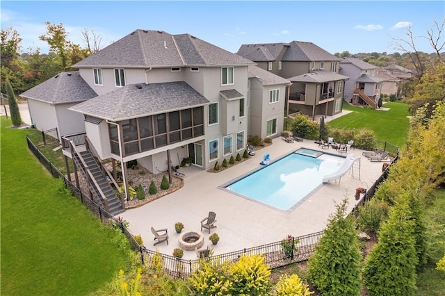 view of pool featuring a yard, a sunroom, a patio area, a water slide, and stairs