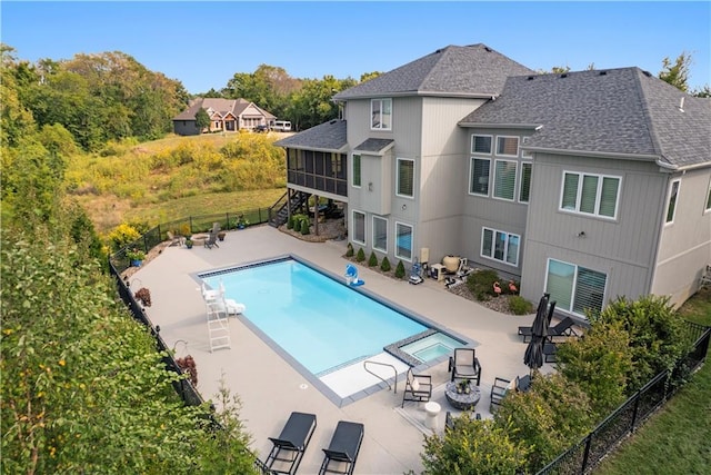 view of pool with a patio, a pool with connected hot tub, a sunroom, fence, and a fire pit