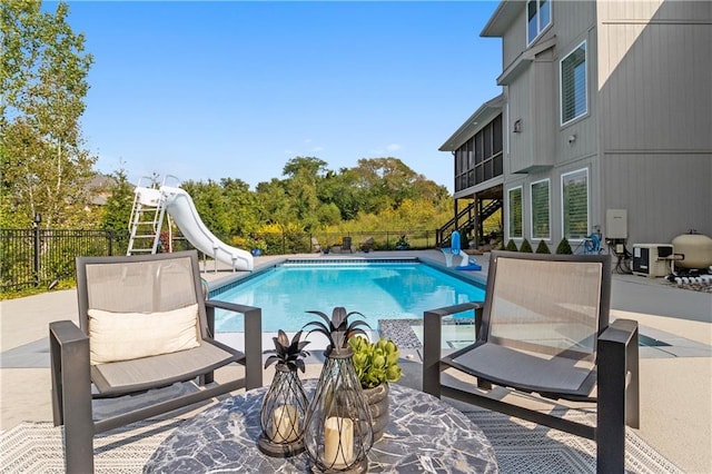 view of pool featuring a fenced backyard, a fenced in pool, a water slide, and a patio