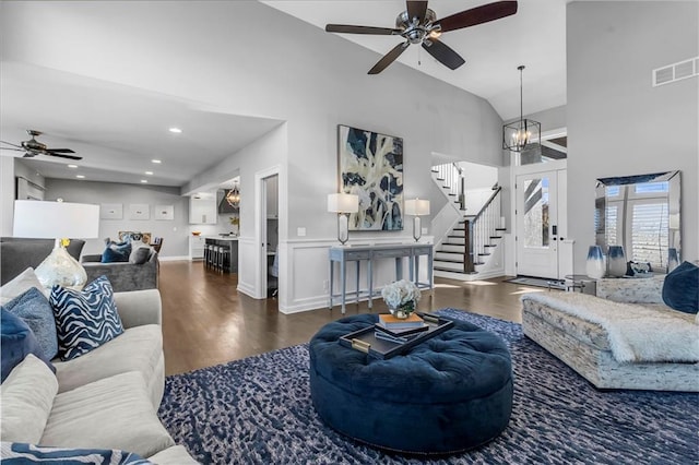 living room with high vaulted ceiling, stairs, visible vents, and wood finished floors