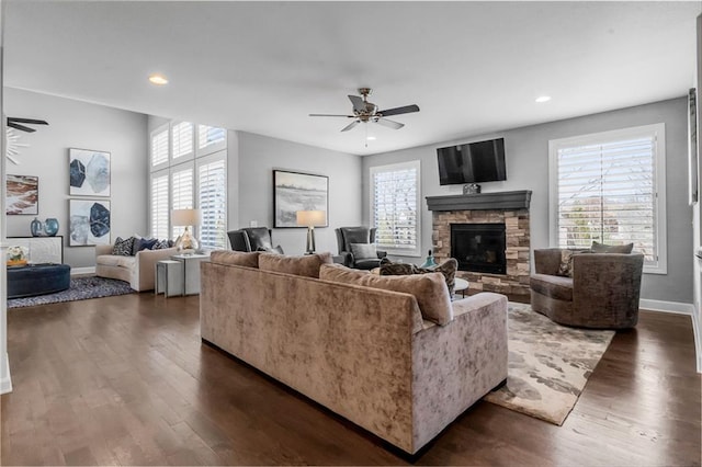 living area featuring dark wood-style floors, a fireplace, baseboards, and a ceiling fan