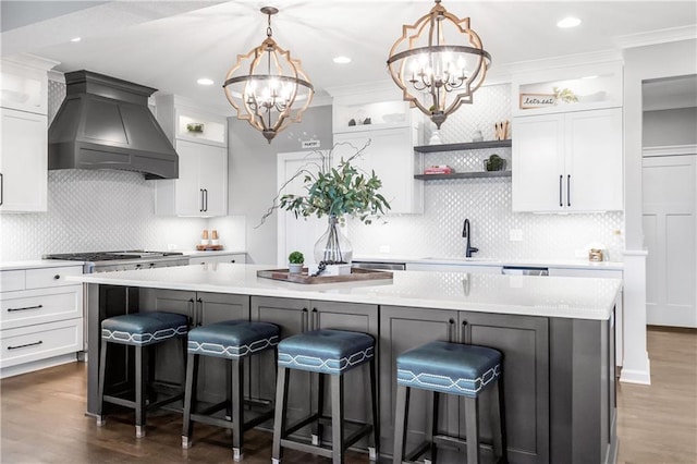 kitchen with an inviting chandelier, custom range hood, white cabinetry, and light countertops