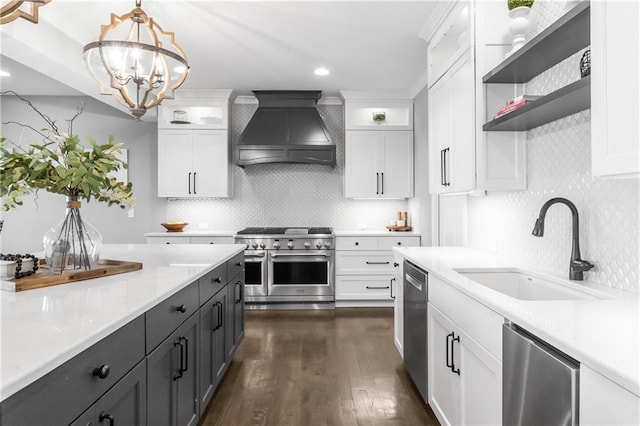 kitchen featuring open shelves, light countertops, custom range hood, appliances with stainless steel finishes, and a sink