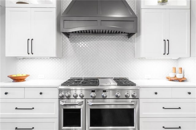 kitchen with light countertops, premium range hood, white cabinetry, and double oven range