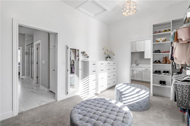 walk in closet with a sink, attic access, and light colored carpet