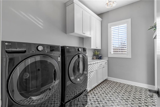 clothes washing area with baseboards, cabinet space, and washing machine and clothes dryer