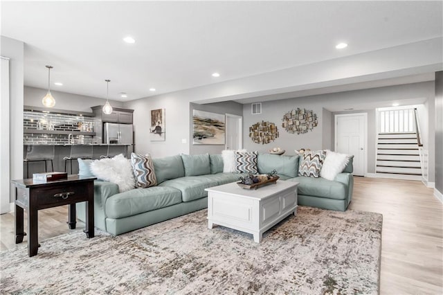 living room with light wood-type flooring, baseboards, stairway, and recessed lighting