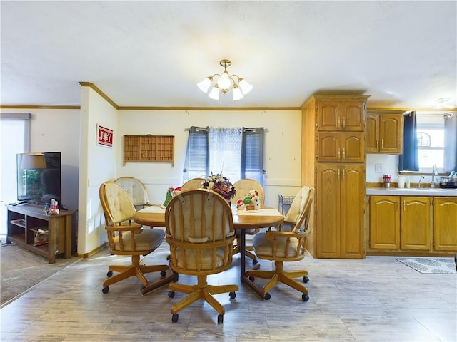 dining space with sink, ornamental molding, and an inviting chandelier