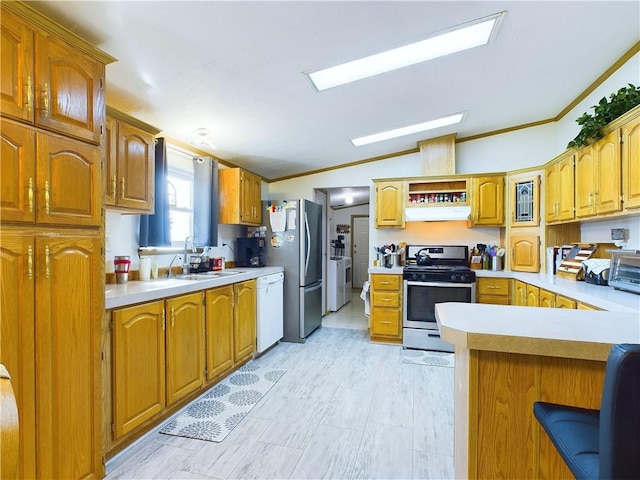 kitchen featuring lofted ceiling, stainless steel appliances, sink, ornamental molding, and a breakfast bar