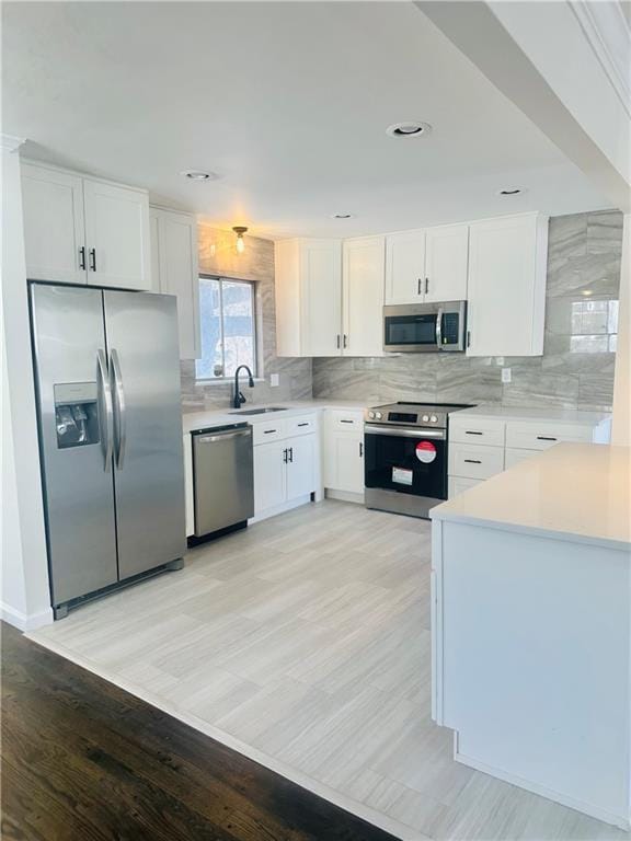 kitchen featuring white cabinets, appliances with stainless steel finishes, light hardwood / wood-style flooring, and sink