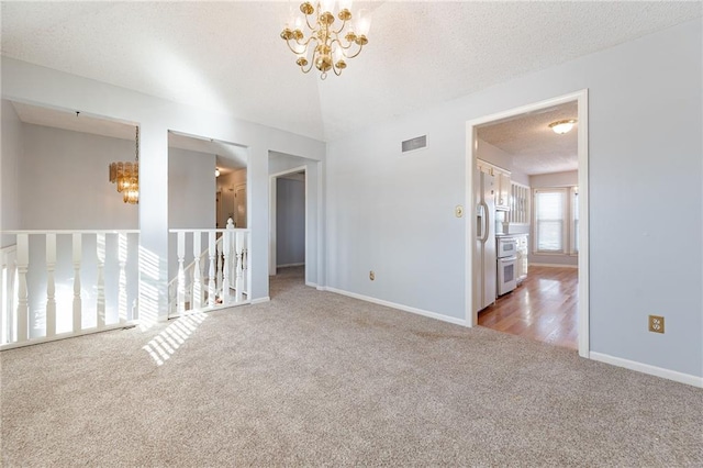 carpeted spare room with a textured ceiling, lofted ceiling, and a chandelier