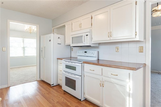 kitchen with backsplash, white appliances, light wood-type flooring, a textured ceiling, and white cabinets