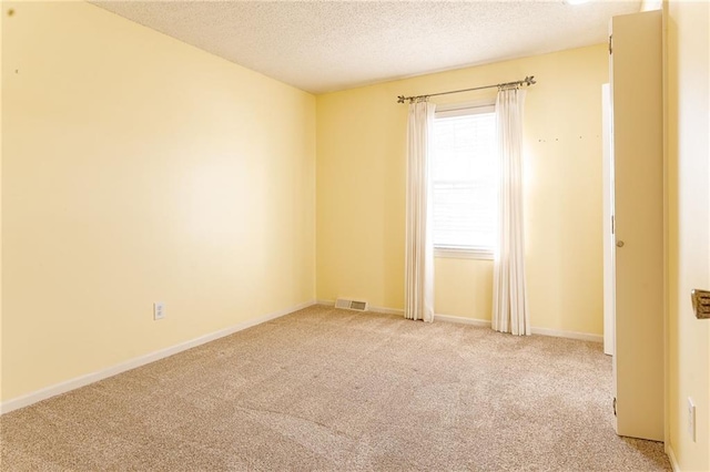 empty room with a textured ceiling and light carpet