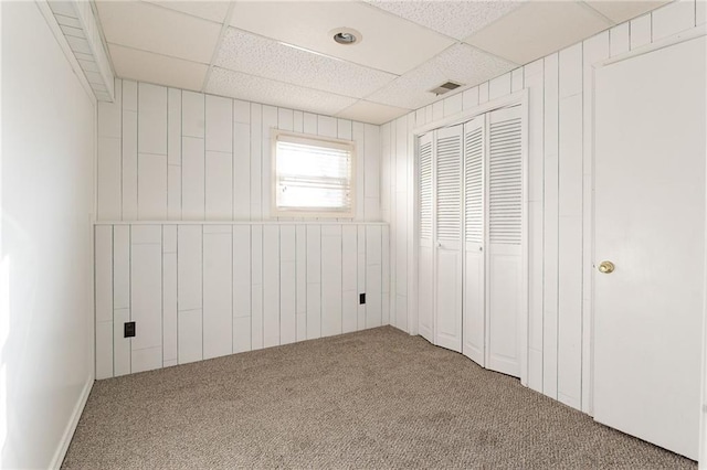 unfurnished bedroom with a paneled ceiling, a closet, and carpet flooring