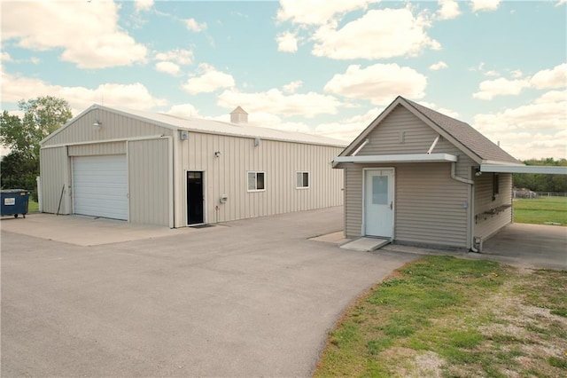view of front of house with a detached garage and an outbuilding