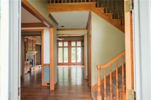 interior space featuring ceiling fan, ornamental molding, a fireplace with raised hearth, and wood finished floors