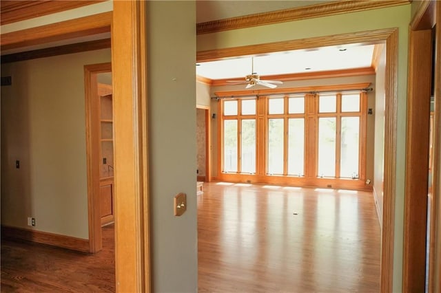 spare room featuring crown molding, baseboards, ceiling fan, and wood finished floors