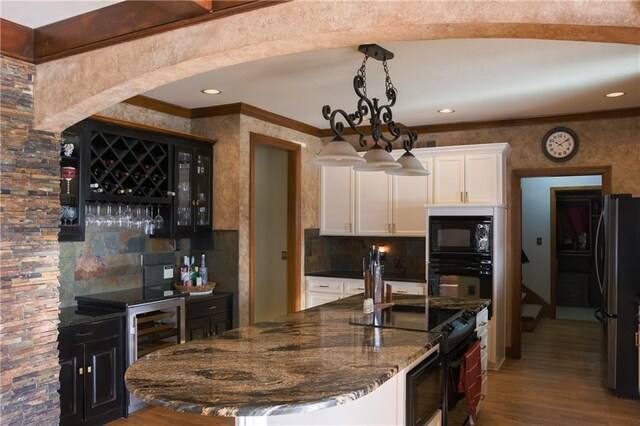 kitchen featuring white cabinetry, crown molding, wood finished floors, black appliances, and dark stone counters
