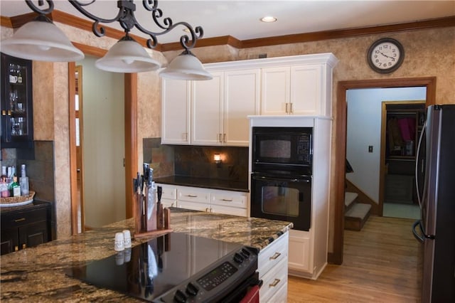 kitchen with dark stone countertops, light wood-type flooring, black appliances, backsplash, and white cabinets