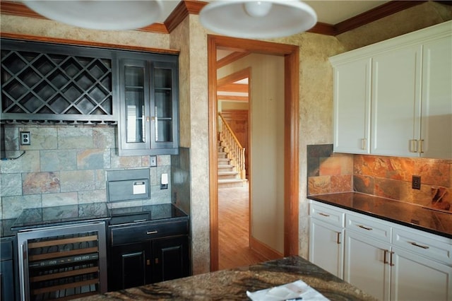 kitchen with beverage cooler, white cabinetry, decorative backsplash, and crown molding