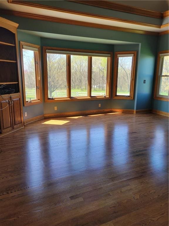 unfurnished room with baseboards, dark wood-style flooring, and crown molding