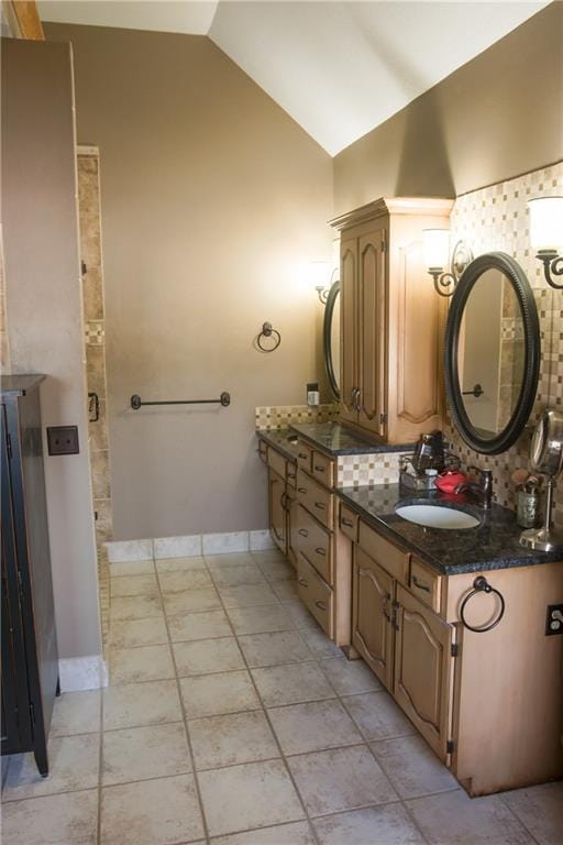 bathroom featuring decorative backsplash, vaulted ceiling, baseboards, and vanity