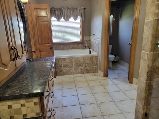 bathroom featuring tile patterned flooring, toilet, a bath, and vanity