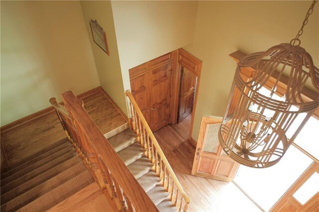 stairs featuring a towering ceiling, baseboards, and wood finished floors