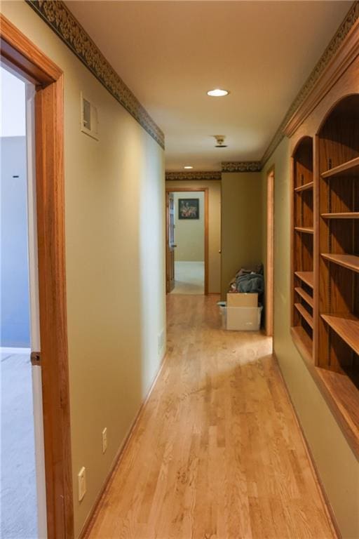 hallway featuring crown molding, light wood-type flooring, visible vents, and recessed lighting