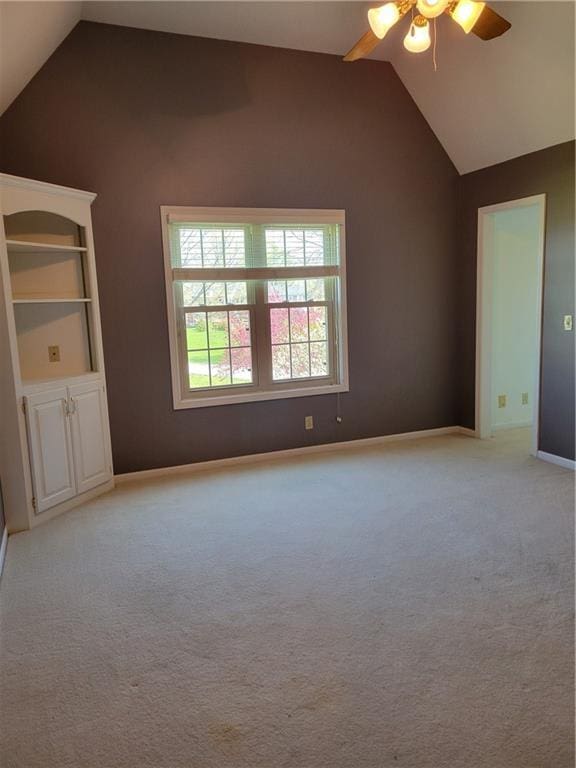 interior space featuring vaulted ceiling, light carpet, baseboards, and a ceiling fan