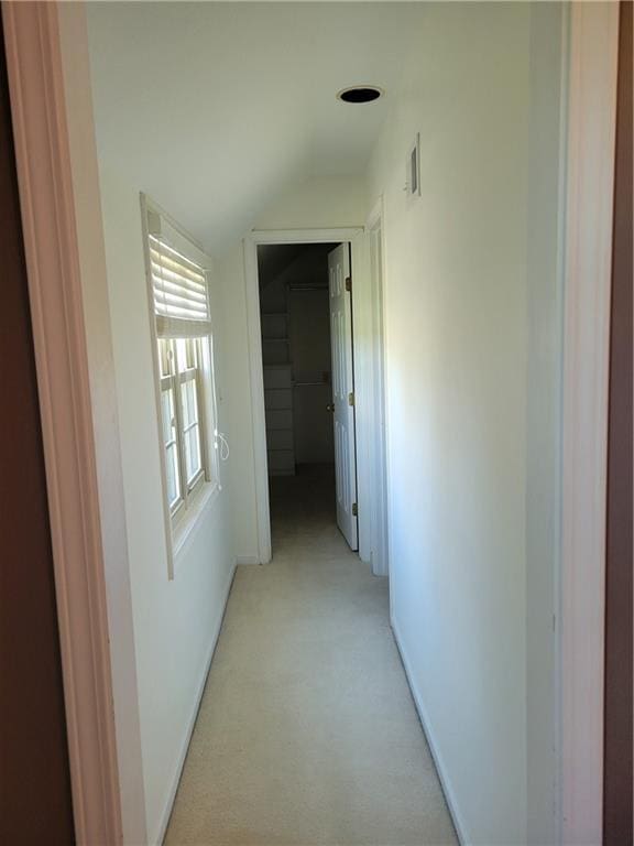 corridor featuring light colored carpet, lofted ceiling, baseboards, and visible vents