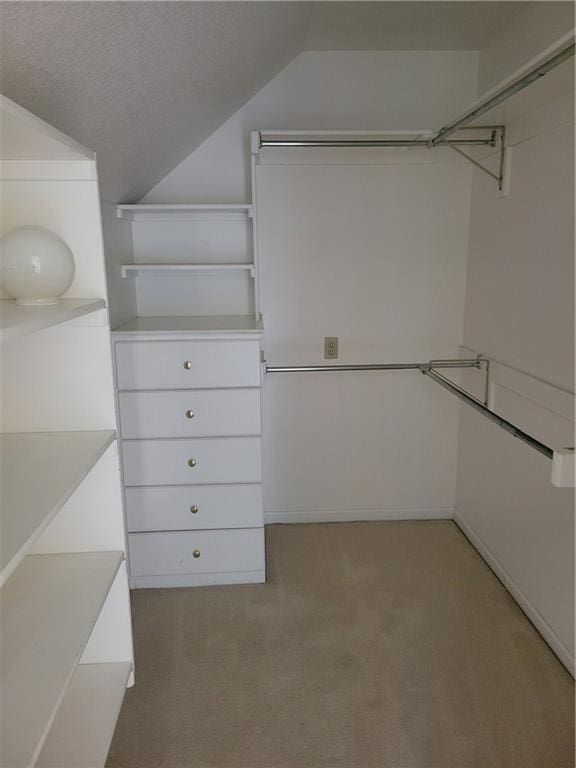 spacious closet with lofted ceiling and light carpet