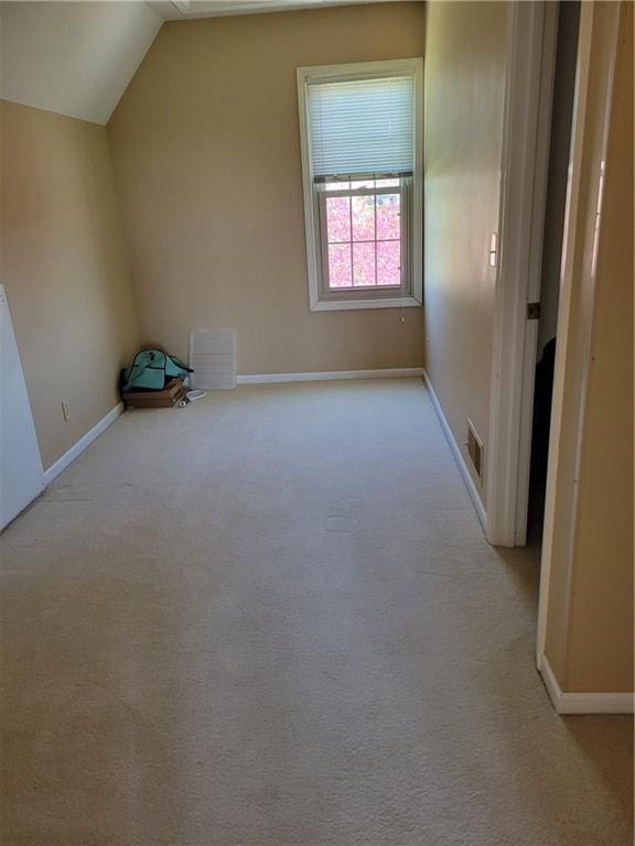 additional living space featuring light carpet, lofted ceiling, baseboards, and visible vents