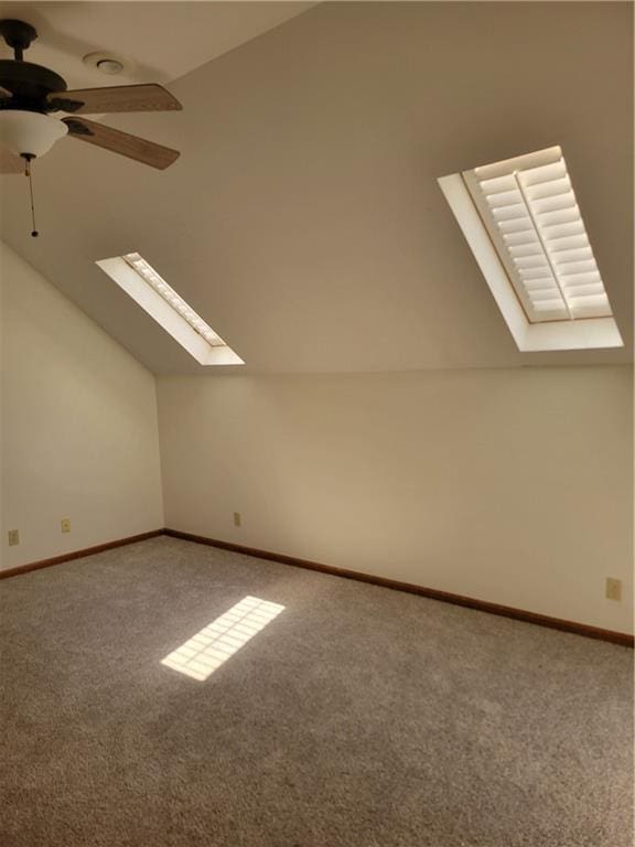 bonus room featuring a ceiling fan, carpet floors, baseboards, and vaulted ceiling with skylight