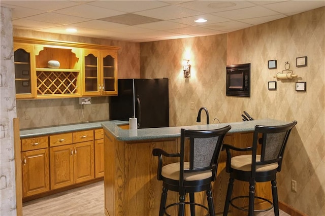 bar featuring freestanding refrigerator, wet bar, and light wood-type flooring