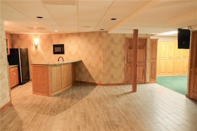 bar featuring freestanding refrigerator, a paneled ceiling, light wood-style flooring, and indoor wet bar
