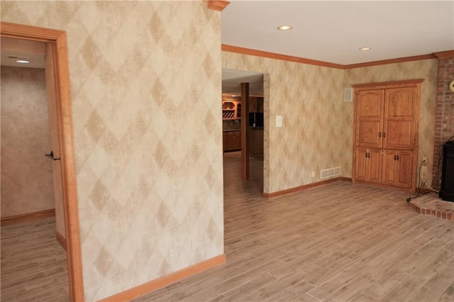 empty room with baseboards, light wood-style floors, visible vents, and wallpapered walls