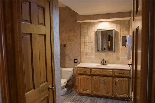 bathroom with toilet, vanity, and wood finished floors