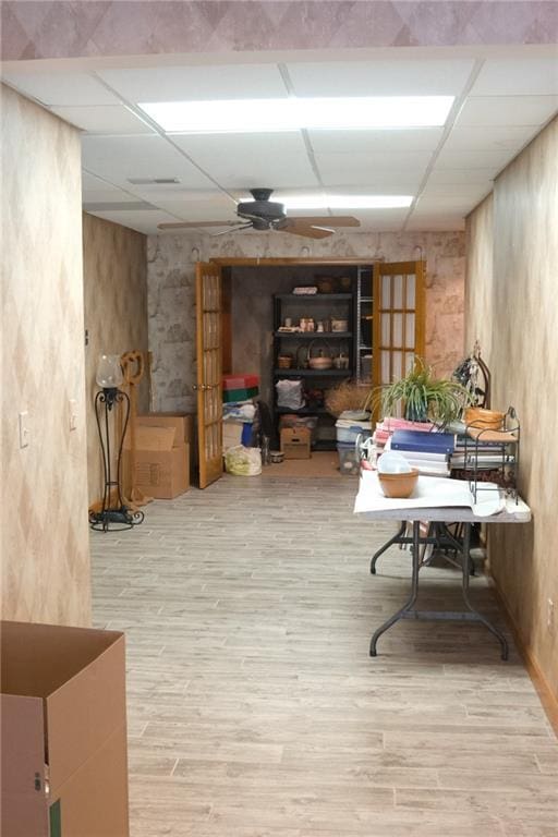 basement with wood finished floors, a ceiling fan, and a paneled ceiling