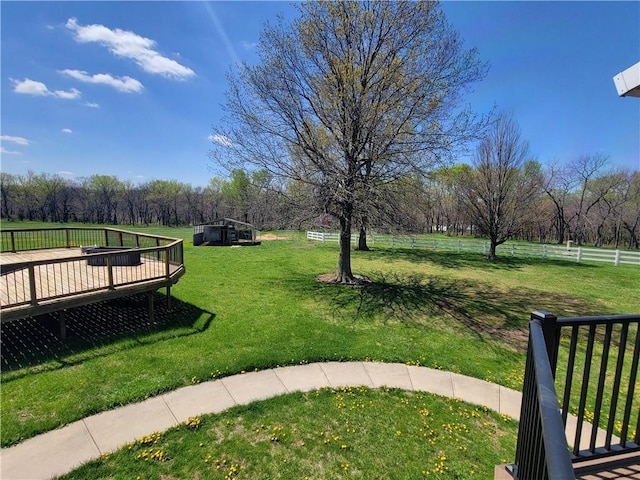 view of community with a yard, a wooden deck, and fence