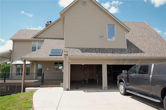 view of front of property featuring an attached garage, concrete driveway, a shingled roof, and a chimney