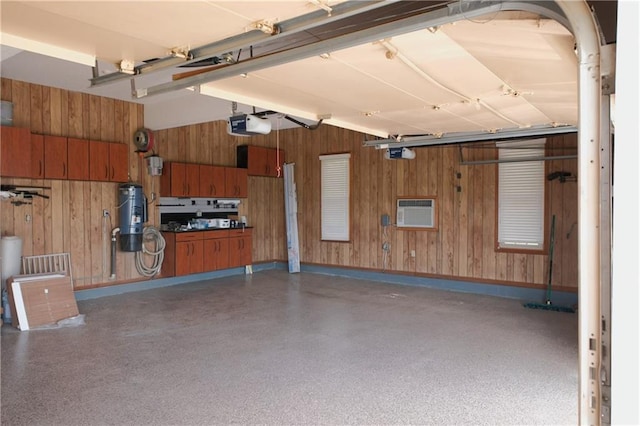 garage featuring wood walls, a garage door opener, and a wall unit AC