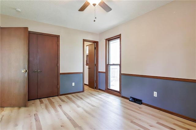 unfurnished bedroom featuring ceiling fan, light wood-type flooring, and a closet