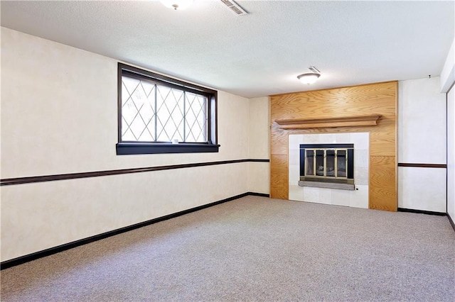 unfurnished living room featuring a textured ceiling, a tile fireplace, and carpet flooring