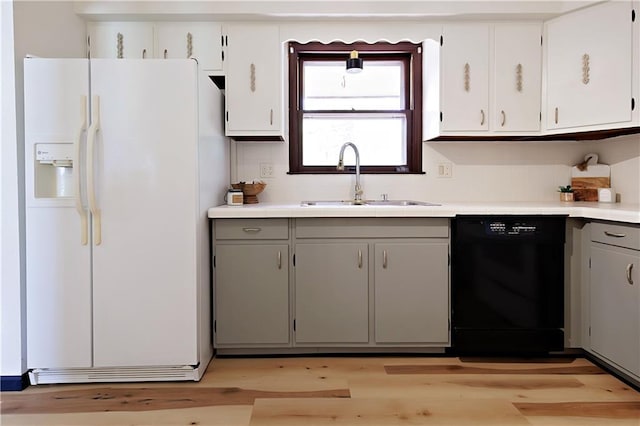 kitchen featuring white cabinets, white refrigerator with ice dispenser, black dishwasher, light hardwood / wood-style floors, and sink