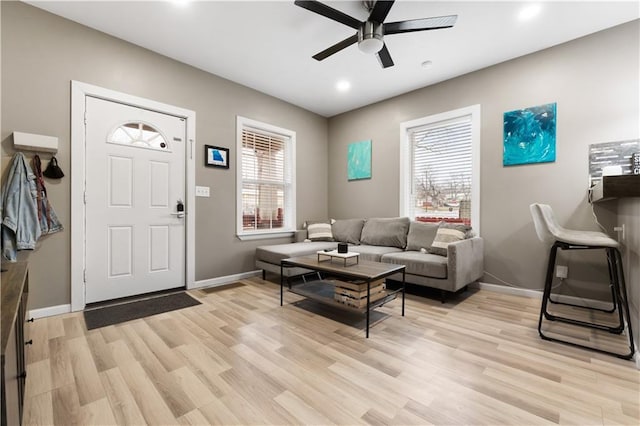 living room featuring ceiling fan, light wood-type flooring, and a wealth of natural light