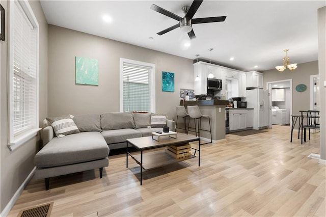 living room with a healthy amount of sunlight, ceiling fan with notable chandelier, and light hardwood / wood-style flooring