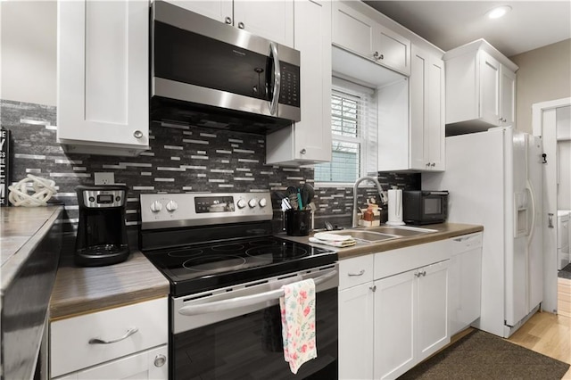 kitchen featuring sink, white cabinetry, appliances with stainless steel finishes, light hardwood / wood-style floors, and backsplash